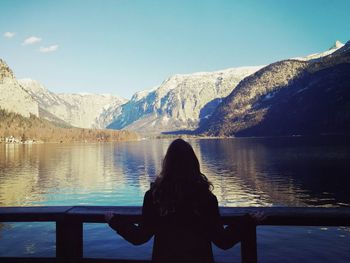 Rear view of silhouette woman standing by lake against sky