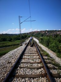 Women walking on railroad track against sky