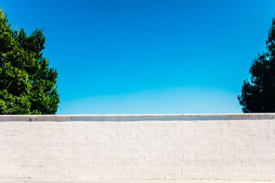 Low angle view of wall against clear blue sky