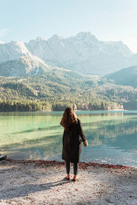 Rear view of woman standing against lake