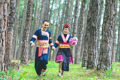 Women standing by tree trunk in forest