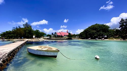 Boats in swimming pool by sea against blue sky