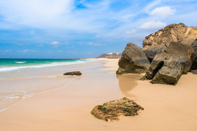 Rock formation on beach against sky