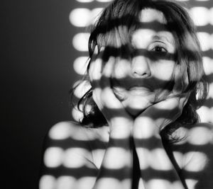 Close-up portrait of young woman against gray background