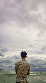 Rear view of man looking at sea against sky