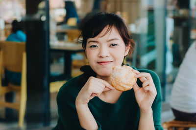 Portrait of smiling woman eating food at restaurant