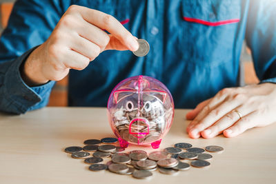 Close-up of hand holding coins on table