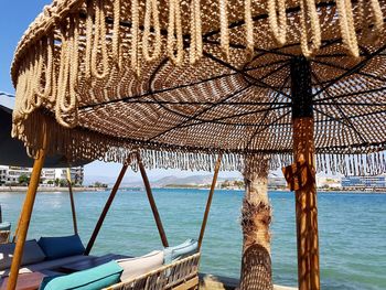 Close-up of thatched roof at beach against sky