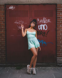 Full length of woman standing against wall