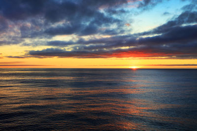 Scenic view of sea against dramatic sky during sunset