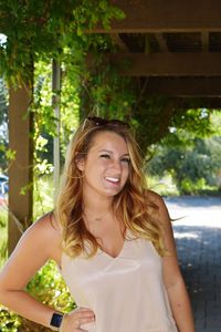 Portrait of smiling young woman standing against tree