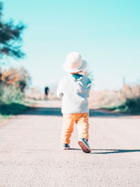 Full length of boy standing on road against sky