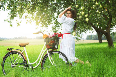 Side view of woman with bicycle on field