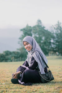 Portrait of smiling young woman sitting on field