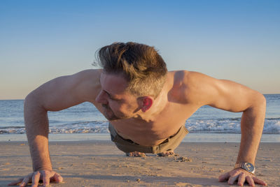 Shirtless man exercising at beach