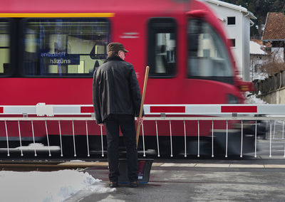 Rear view of man standing by railway crossing