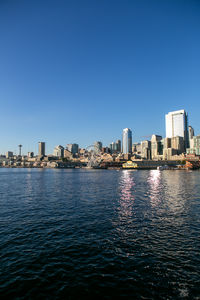 Sea by buildings against clear blue sky