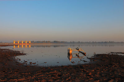 Scenic view of lake against clear sky at sunset