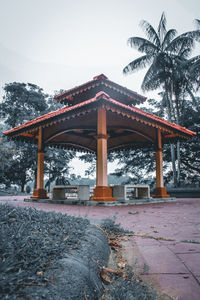 Gazebo by palm trees against clear sky