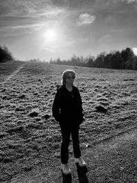 A person standing in a field, looking into the camera