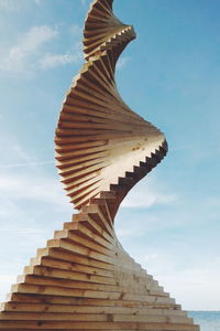 Low angle view of wooden spiral sculpture against sky