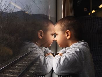 Side view of boy looking through train window in journey