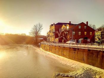 Buildings by river against clear sky