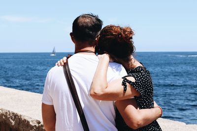 Rear view of couple kissing against sea