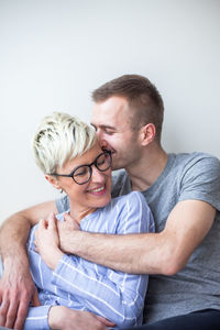 Happy couple sitting by wall at home