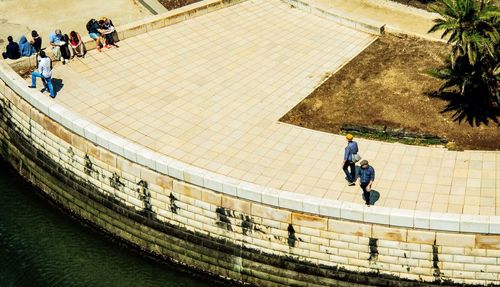 High angle view of people at pedestrian zone by river on sunny day