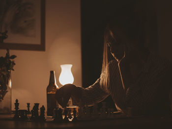 Midsection of woman with wine bottles on table at home