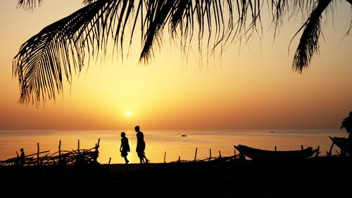 Silhouette man standing on beach against sky during sunset