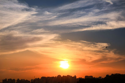 Silhouette cityscape against sky during sunset