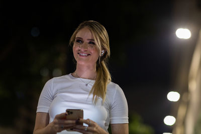 Woman using a smartphone at night time on the street. mobile phone, technology, urban .