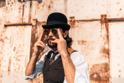 Full length of young man photographing against wall