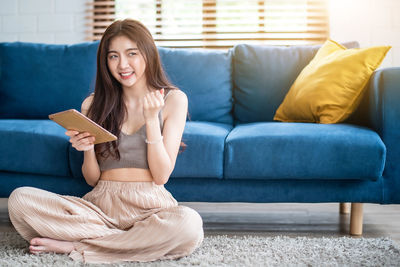 Portrait of smiling woman sitting on sofa at home