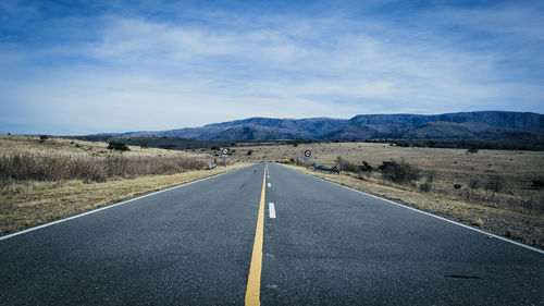 Road leading towards mountains against sky