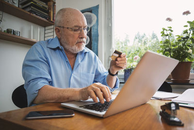 Senior man using credit card for bill payment at home