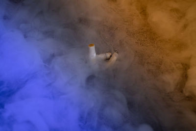 High angle view of cigarette butts amidst smoke on field