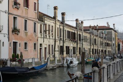 Boats moored in canal by buildings in city