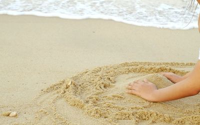 Cropped hands of child making sandcastle at beach