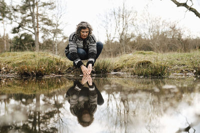 Female explorer washing hands in lake at forest