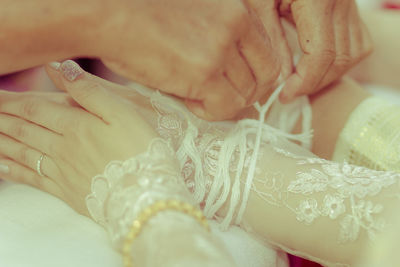 Cropped hands of woman tying bride wrist