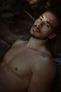 Portrait of shirtless young man sitting in lake