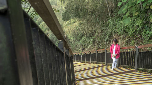 Rear view of woman standing on footbridge