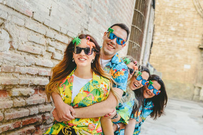 Portrait of young woman wearing sunglasses standing against brick wall