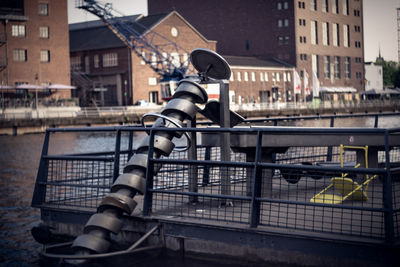 Bicycle on railing by river against buildings in city