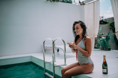 Young woman drinking water from swimming pool