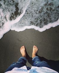 Low section of man standing on shore at beach