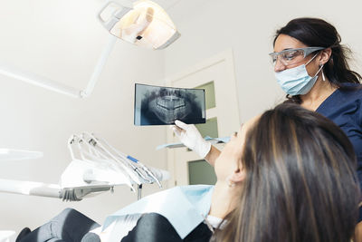 Female dentist showing x-ray to patient sitting in hospital